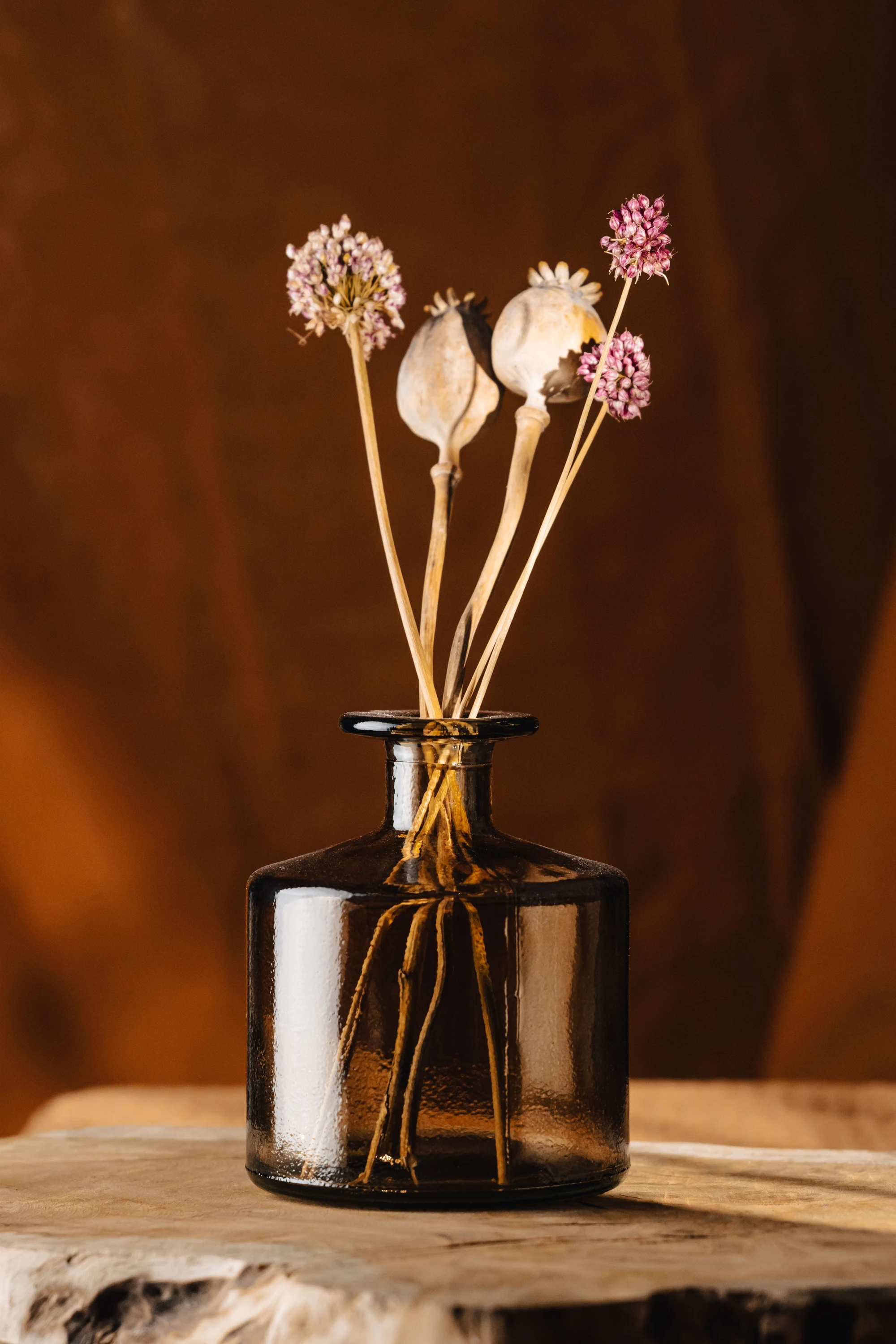 Delicate dried flowers in an amber glass vase